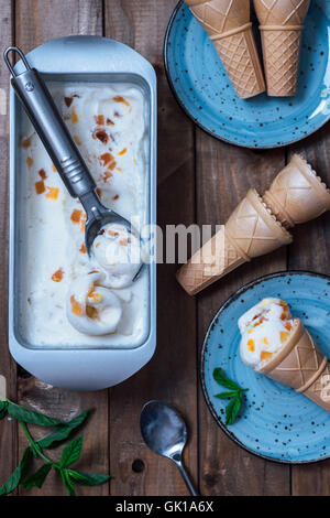 Peach gelato in una padella e servita con i coni su due piastre di blu. Foto Stock