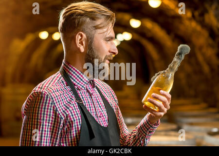 Sommelier con bottiglia di vino in una cantina Foto Stock