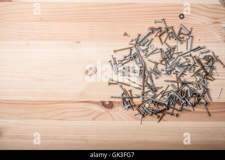 Un assortimento di dadi e bulloni su un tavolo di legno sfondo Foto Stock