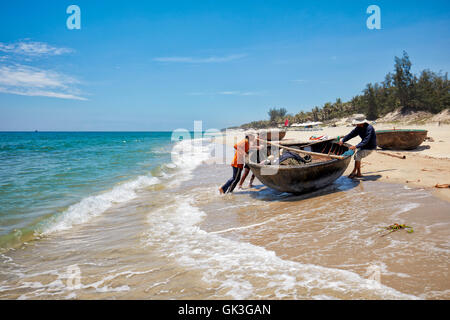 I pescatori vietnamiti tirare coracle sulla spiaggia di Cua Dai. Hoi An, Quang Nam Provincia, Vietnam. Foto Stock