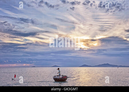 Il vietnamita coracle pescatore. Spiaggia di Cua Dai, Hoi An, Quang Nam Provincia, Vietnam. Foto Stock