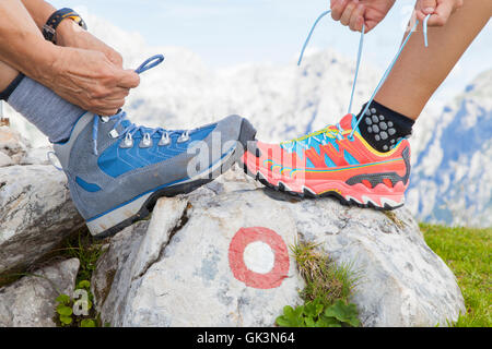 Due escursionisti di avvio legatura lacci, in alta montagna Foto Stock