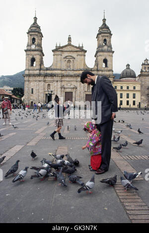 Ca. 1980-1995, Bogotà·, Colombia --- una giovane ragazza alimenta i piccioni al di fuori di Bogotà la cattedrale nazionale nella piazza principale. La Colombia. Foto Stock