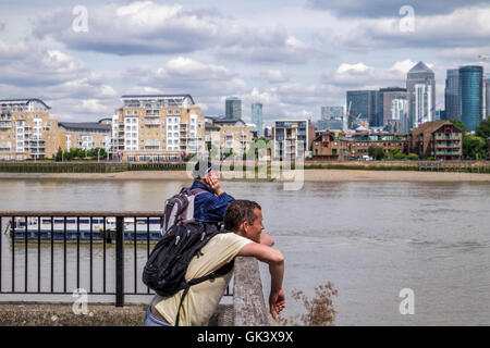 Greenwich, Regno Unito . Giovane uomo e uomo senior di guardare a vista del fiume Tamigi, Isle of Dogs & Canary Wharf, Londra Foto Stock