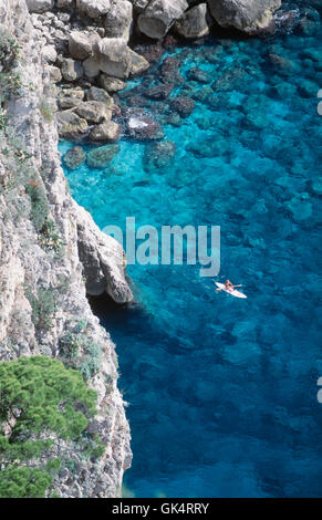 2004, Capri, Italia --- Una kayaker esplora le acque turchesi ai piedi delle scogliere vicino ai Faraglioni. --- Image by © ger Foto Stock