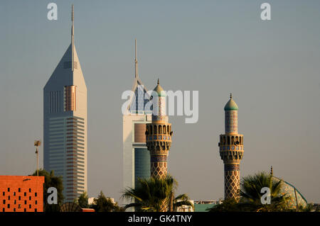 2006, Dubai, Emirati Arabi Uniti --- Emirates Towers dwarf minareti di una moschea locale nel distretto di Jumeirah a Dubai. -- Foto Stock