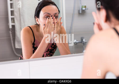 Vicino la giovane donna faccia il lavaggio in piedi di fronte a specchio nel moderno bagno piastrellato a casa Foto Stock