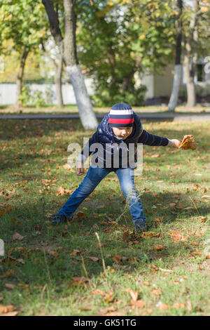 Il ragazzino passeggiate sulla città di autunno con foglie di giallo Foto Stock