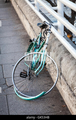 I resti di una bicicletta che è stato vandalizzato sono ancora bloccati alla ringhiera di un ponte Foto Stock