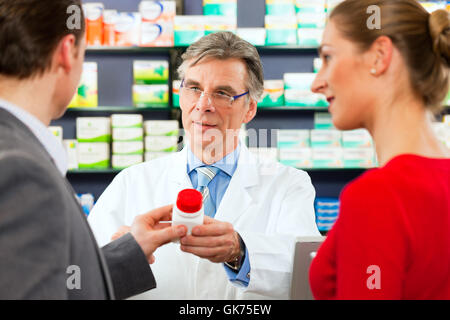 Il farmacista nella sua farmacia con i clienti Foto Stock