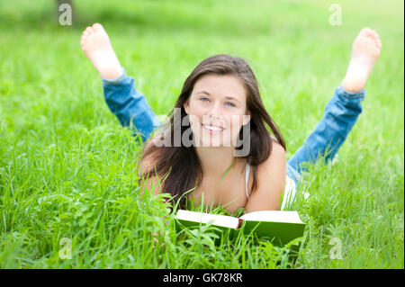 Ragazza giovane e carina è la lettura in erba Foto Stock