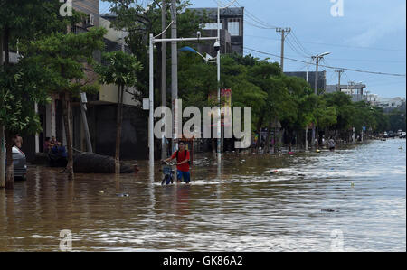 Lingao, la Cina della provincia dell'isola di Hainan. 19 Ago, 2016. Un wades residente su una strada allagata in Lingao County, Cina del sud della provincia dell'isola di Hainan, 19 Agosto, 2016. Una pioggia torrenziale che ha colpito l isola da ago. 14 a 19, come questo anno ottavo del tifone Dianmu sbarcati nel sud della Cina di Guangdong, che colpiscono più di 670.000 persone. Credito: Yang Guanyu/Xinhua/Alamy Live News Foto Stock