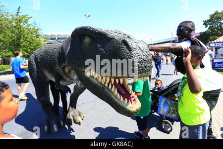 (160819)-- TORONTO, 19 Agosto, 2016(Xinhua) -- i visitatori a giocare con un dinosauro in costume al 2016 Canadian National Exhibition a Toronto, Canada, 19 Agosto, 2016. Come una delle più grandi mostre in Canada, questo annuale 18-evento della durata di un giorno che ha dato dei calci a fuori il venerdì è atteso per attirare più di un milione di visitatori provenienti da tutto il mondo. (Xinhua/Zou Zheng) Foto Stock