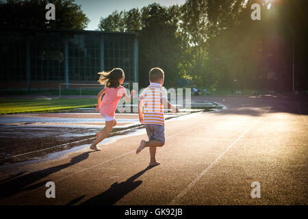 Felice ragazzo e una ragazza correre in pista Foto Stock