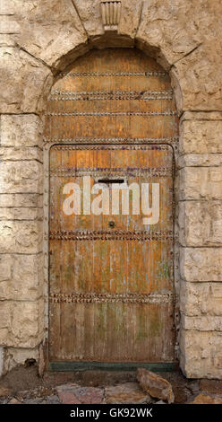 Vecchia porta di legno nel muro di pietra Foto Stock