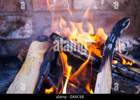 La combustione del legno, fiamma aperta su un mattone costruito per barbecue. Tornitura in legno a carbone. Orange fiamme come il legno brucia in un incendio Foto Stock