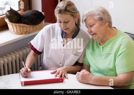 Altenpflegerin durante le visite a domicilio di un paziente Foto Stock