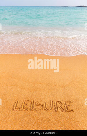 Bellissima spiaggia naturale dal mare blu con la scritta "Tempo libero" realizzato sulla sabbia Foto Stock