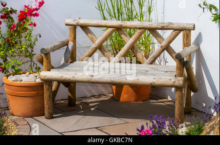 In legno rustico angolo giardino sedile unico sul patio contrassegnati con vasi di piante a Southport Merseyside, Regno Unito Foto Stock