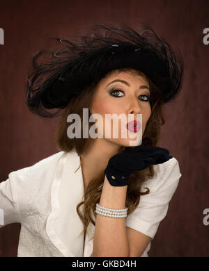 Bruna giovane donna della modellazione di un vintage black hat Foto Stock