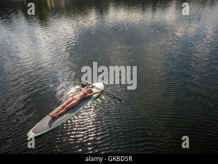 Antenna di una donna che si posa su un stand up paddle board nel lago di cristallo, Virginia Beach, Foto Stock