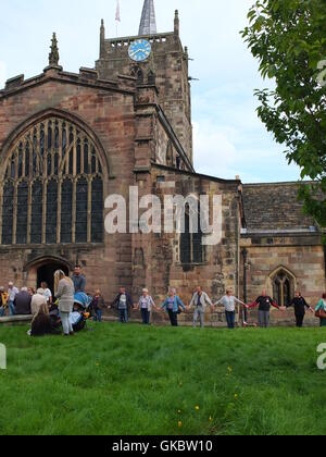 Clypping (o "Clipping") la Chiesa a Wirksworth, Derbyshire - concittadini dei bracci di collegamento e di "abbracciare" la Chiesa. Foto Stock