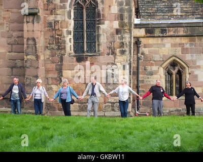 Clypping (o "Clipping") la Chiesa a Wirksworth, Derbyshire - concittadini dei bracci di collegamento e di "abbracciare" la Chiesa. Foto Stock