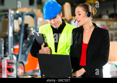 I colleghi nel magazzino di uno spedizioniere dal computer portatile Foto Stock