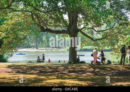 Picnic in famiglia Londra, visualizzare un pomeriggio estivo di turisti avente un picnic accanto al lago in barca a Regent's Park, London, Regno Unito. Foto Stock