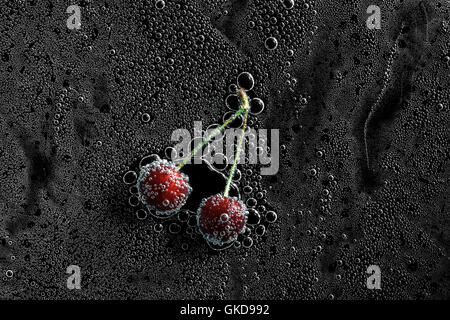 Cherry Berry in acqua minerale, una serie di foto. Close-up di acqua gassata su sfondo nero Foto Stock