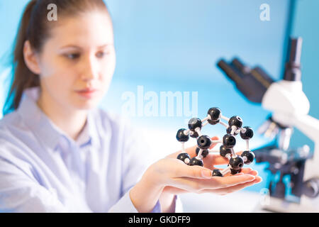 Giovane donna con il modello di molecola in mano Foto Stock