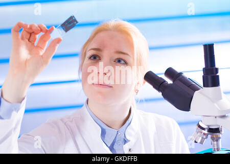 Giovane donna con vetrino per microscopio in laboratorio Foto Stock