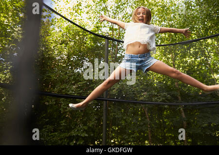 Ragazza stella fa saltare sul trampolino in un giardino Foto Stock