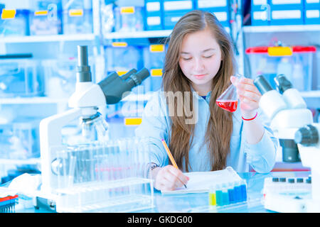 Teen schoolgirl nella classe chimica con tubi di prova Foto Stock