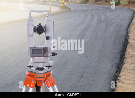 Sondaggio teodolite attrezzature su un treppiede. con la strada in costruzione sullo sfondo Foto Stock