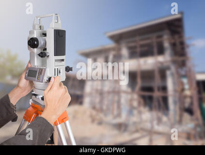 Lavorazione a mano con attrezzature di indagine teodolite su un treppiede. Con la costruzione di edifici di sfondo del sito Foto Stock