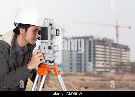 I tecnici utilizzano tacheometer o teodolite con la costruzione di edifici di sfondo del sito Foto Stock