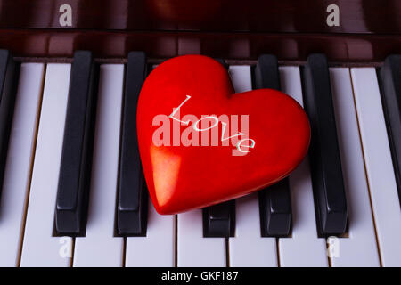 Rosso brillante cuore sui tasti di pianoforte Foto Stock