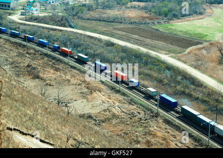 Treno merci in movimento lungo su uno sfondo di colore verde valle di primavera Foto Stock