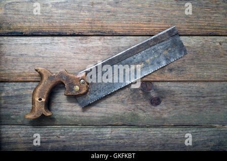 Retrò rusty trasversale sega a mano strumento handsaw isolato su sfondo di legno Foto Stock