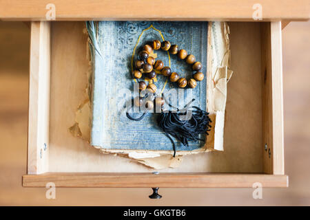 Al di sopra di vista del rosario in squallido Libro religioso in aprire il cassetto del comodino Foto Stock