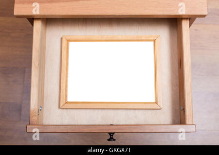 Vista al di sopra del legno picture frame con tagliare il nastro in aprire il cassetto del comodino Foto Stock