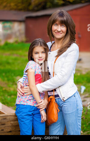 Close up ritratto di un bellissimo nove anni di bambina e madre felice in autunno park Foto Stock