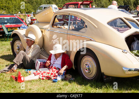 L uomo e la donna godendo picnic accanto al loro classico1938 Triumph Vitesse autovettura presso il vapore Shabibngton rally Oxfordshire England Regno Unito Foto Stock