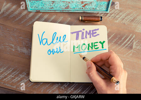 Effetto retrò e tonico immagine di una donna la scrittura a mano una nota con una penna stilografica su un notebook. Foto Stock