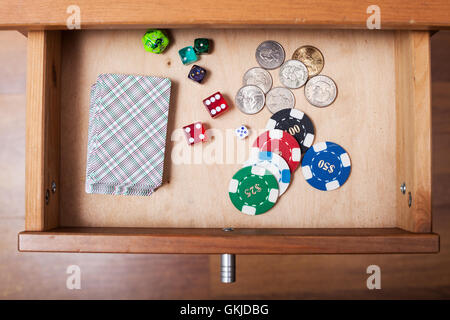 Vista superiore del mazzo di carte da gioco, cubetti, casino chip e monete in aprire il cassetto del comodino Foto Stock