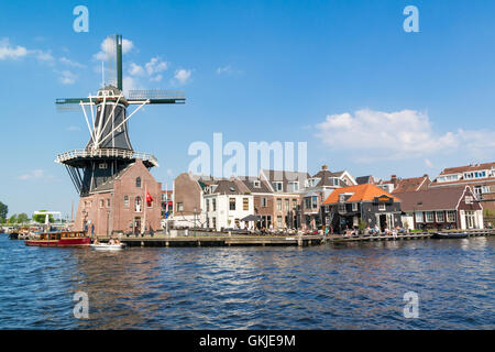 Barche, windmill Adriaan e persone su waterfront cafe accanto al fiume Spaarne in Haarlem, Paesi Bassi Foto Stock