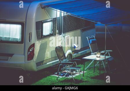 Rimorchio di viaggio Camping romantico Setup. Moderno rimorchio di viaggio e Mobili Campeggio sotto la tenda. Moderno Caravaning. Foto Stock