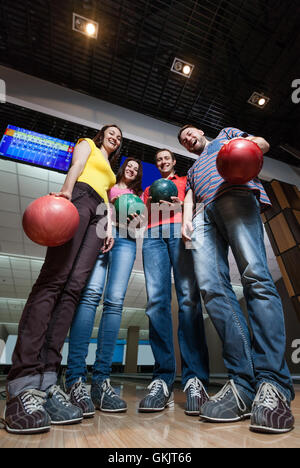 Amici divertendosi in bowling Foto Stock