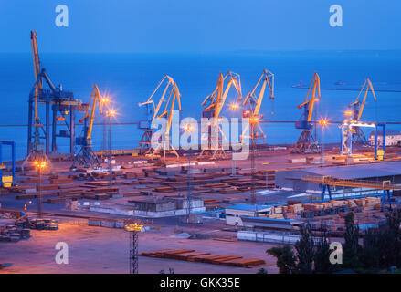 Porto commerciale di notte in Mariupol, Ucraina. Paesaggio industriale. Merci spedite con gru di lavoro bridge Foto Stock